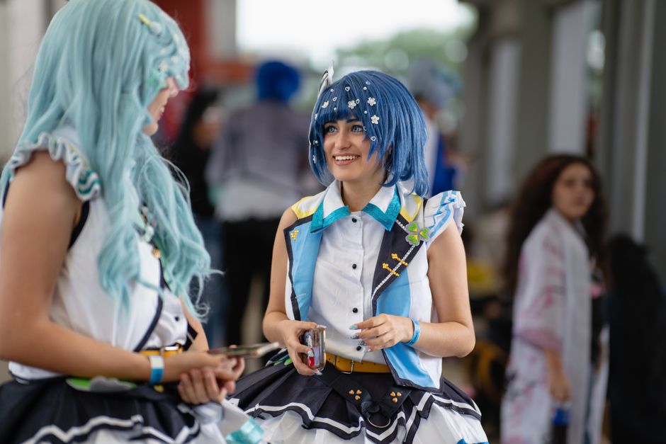 Cosplayers dressed as anime characters at a bustling convention center.